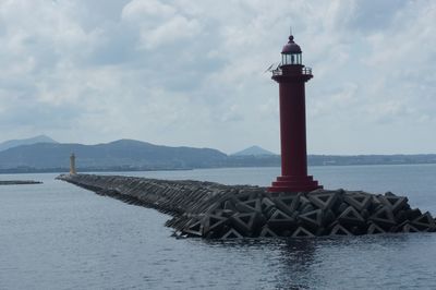 Lighthouse by sea against sky