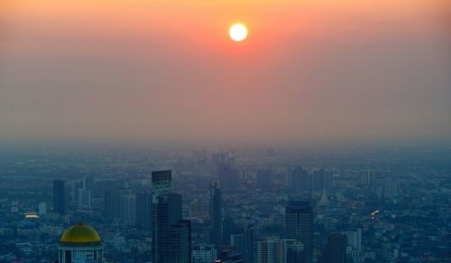 Aerial view of buildings in city against sky during sunset