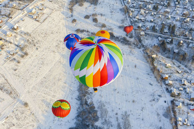 High angle view of hot air balloons flying over snow covered land