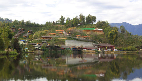 Scenic view of lake by buildings against sky