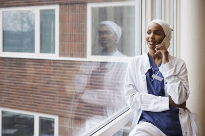 Young female doctor talking on phone at work