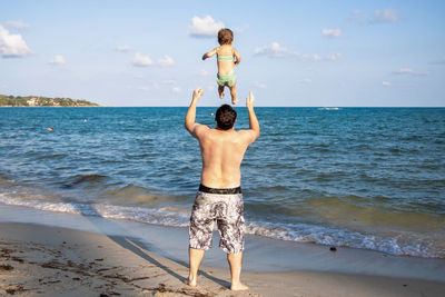 Rear view of of a man throwing a young child up into the air