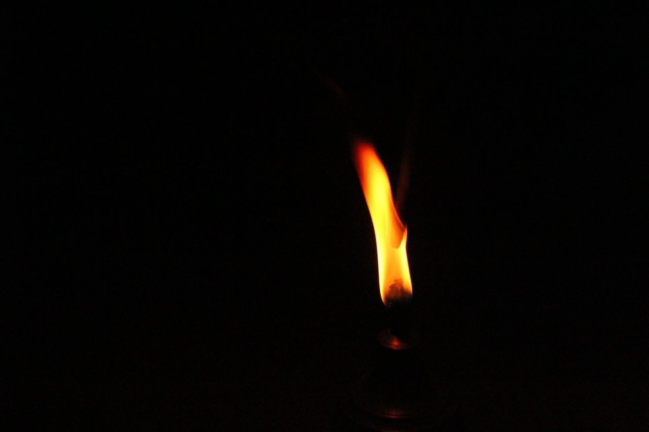 CLOSE-UP OF ILLUMINATED LIGHT CANDLE IN DARKROOM