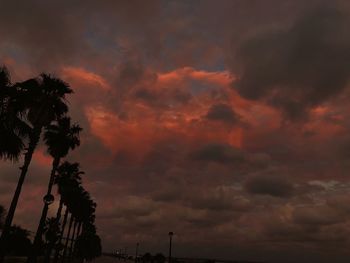 Low angle view of silhouette trees against dramatic sky