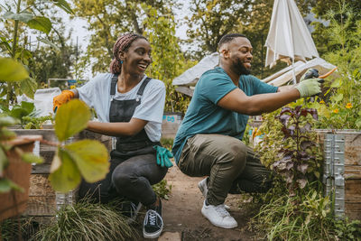 Happy male and female volunteers planting flowers during agricultural training at garden