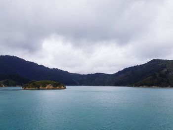 Scenic view of sea by mountains against sky