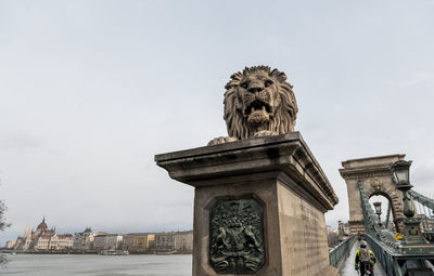 Statue in city against sky