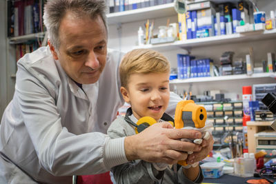 Grandfather assisting grandson in using equipment at store