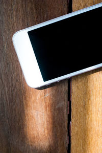 High angle view of smart phone on wooden table