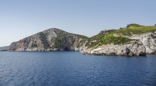 Scenic view of sea and mountains against clear blue sky