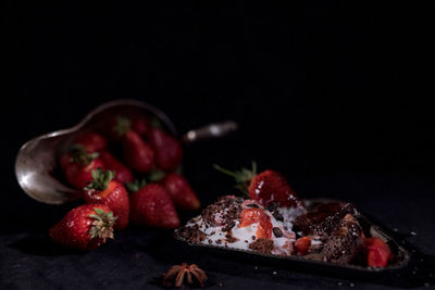 White ice cream with chocolate drops with strawberries on a black background