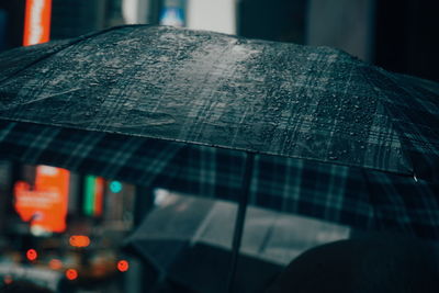 Close-up of wet umbrella in city at night
