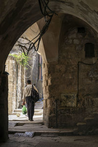 Rear view of woman walking on old building