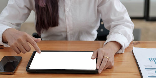 Midsection of woman using smart phone on table