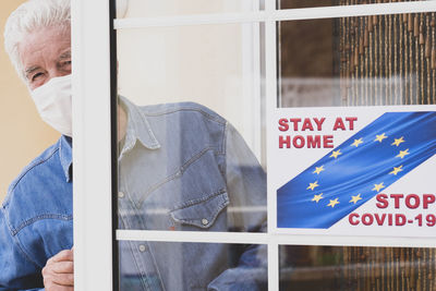 Midsection of man holding text on window