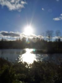 Sun shining over lake against sky on sunny day