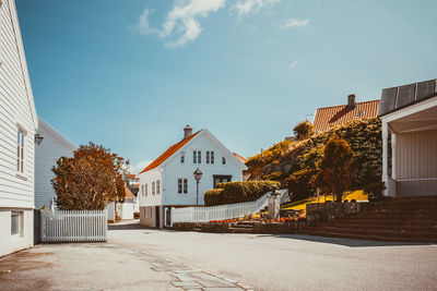 Road amidst trees and buildings against sky