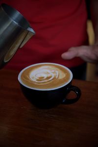 Midsection of woman holding coffee on table