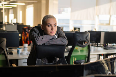 Young woman sitting on chair while looking away