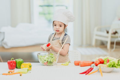 Baby girl eating food in kitchen