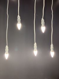 Low angle view of illuminated light bulbs hanging from ceiling