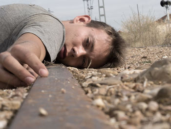 Close-up of man shouting while lying on railroad track