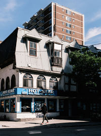Man walking on street by building against sky