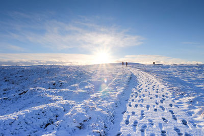 Distant people walking on snow covered field
