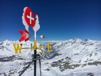Information sign against snowcapped mountains against clear blue sky