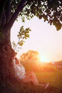Woman on field against sky at sunset