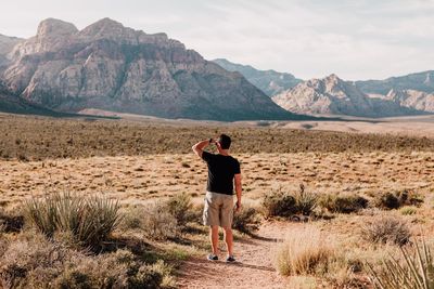 Rear view full length of man standing at desert against sky