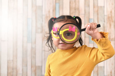 Portrait of cute boy standing against yellow wall