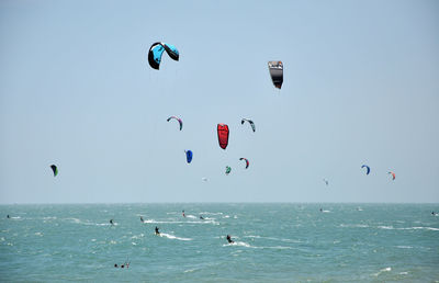 People kiteboarding on sea against clear sky