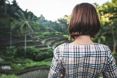 Rear view of woman standing against trees