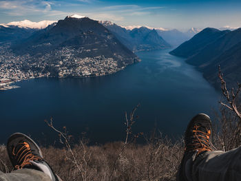 Low section of man standing by lake against mountains during winter