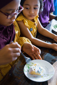 High angle view of girls eating cake on table at home