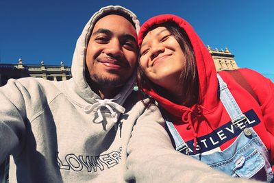 Portrait of smiling young couple against clear sky