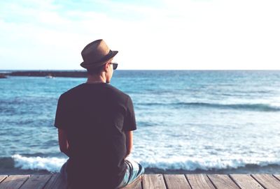 Rear view of man looking at sea against sky