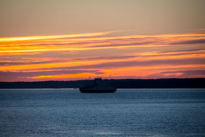 Boat in oslofjord against orange sky during sunset