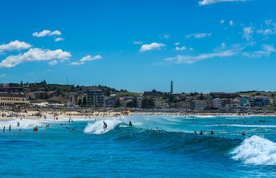 People in the sea against blue sky