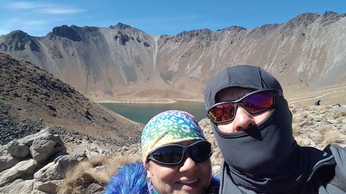 Portrait of people in sunglasses and warm clothing against mountains