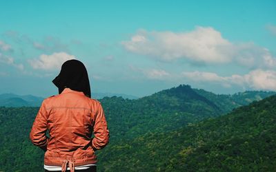 Rear view of woman standing on mountain against sky