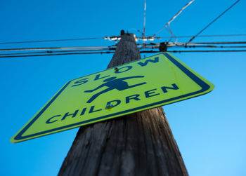 Low angle view of signboard against blue sky