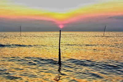 Scenic view of rainbow over sea against sky during sunset