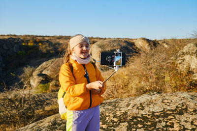 Portrait of woman standing on rock against clear sky