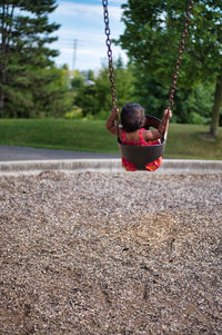 Rear view of girl sitting on swing at playground