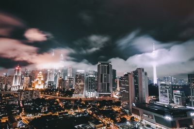 High angle shot of illuminated cityscape against clouds