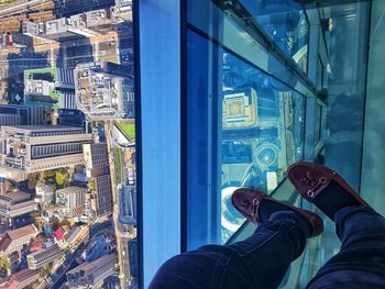 Low section of man with cityscape seen through glass