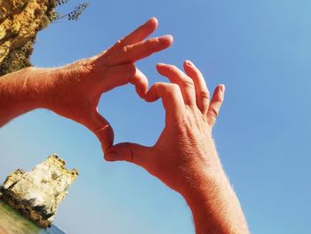 Low angle view of human hand against clear blue sky