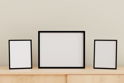 Close-up of blank picture frames on table against gray wall